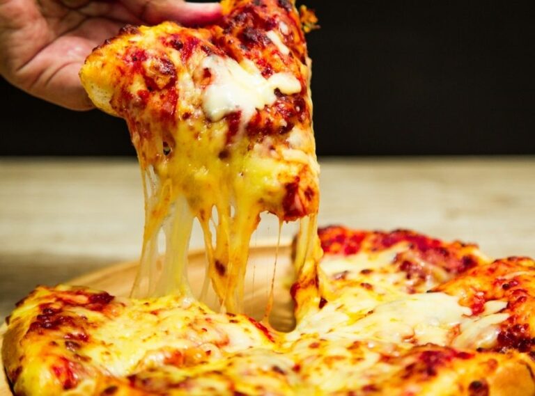 Close-up of cheesy pizza slice being pulled from a fresh hot pizza at one of the best pizza places in Akron Ohio